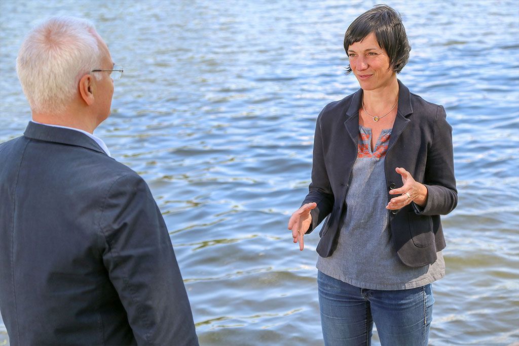 Ein Mann und eine Frau unterhalten sich im Gespräch an einem Gewässer